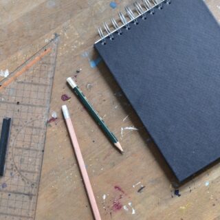notebook with black sheets near stationery on table